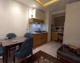میز غذاخوری و کابینت های قهوه ای رنگ آشپزخانه آپارتمان در کلارآباد