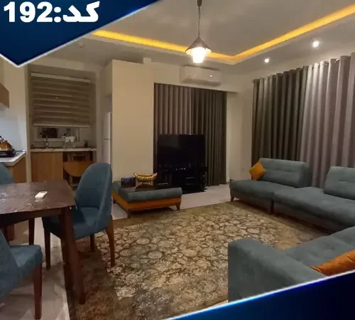 مبلمان آبی رنگ و تلویزیون و سقف نور پردازی شده با نور زرد سالن نشیمن آپارتمان در کلارآباد